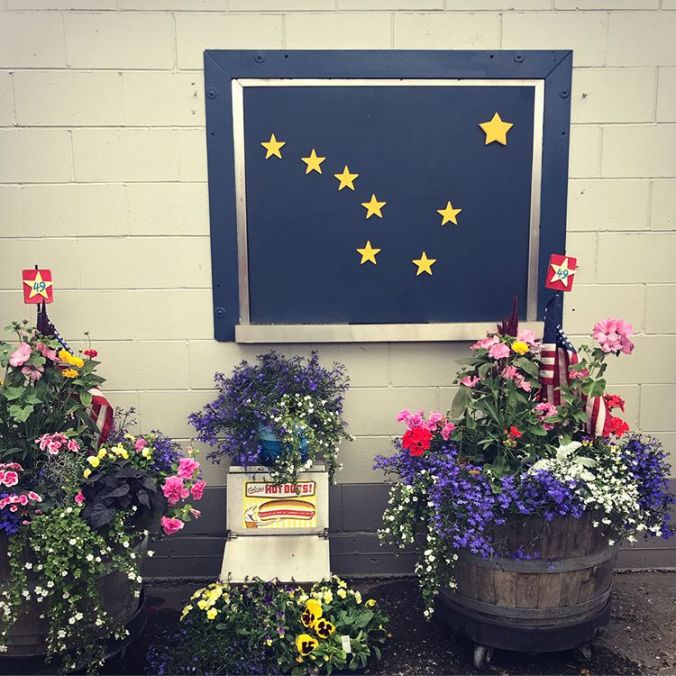 an Alaska flag in front of several pots of flowers
